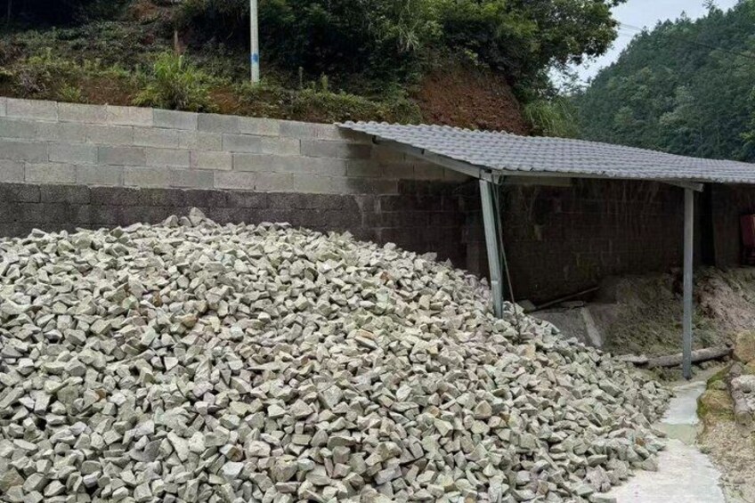 A construction site with a pile of gravel and a partially constructed building with a metal roof. 3