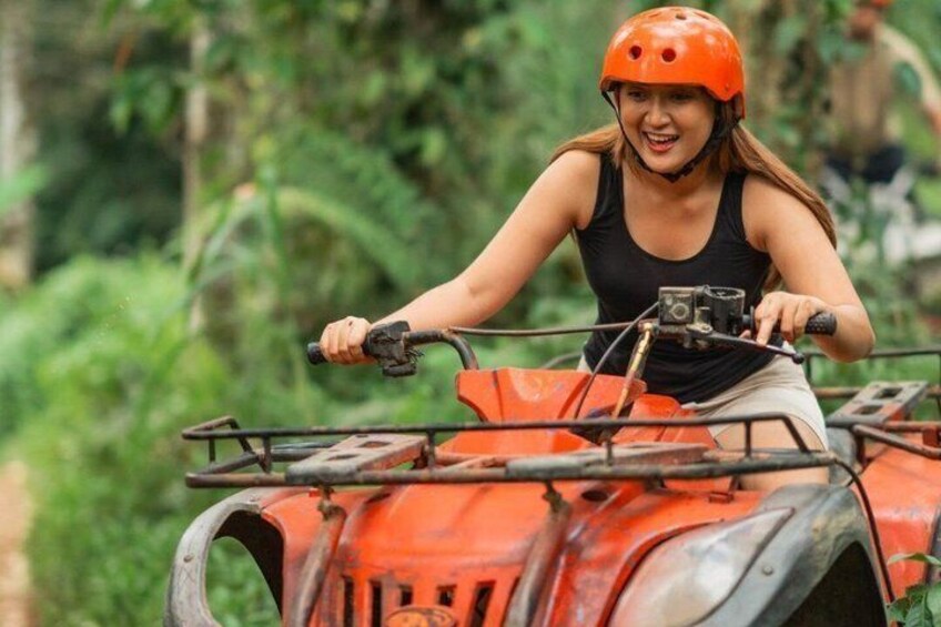 A person riding an orange ATV in a forested area. 3