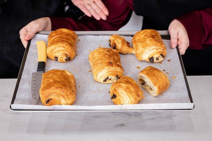 A person holding a tray with several croissants. 4