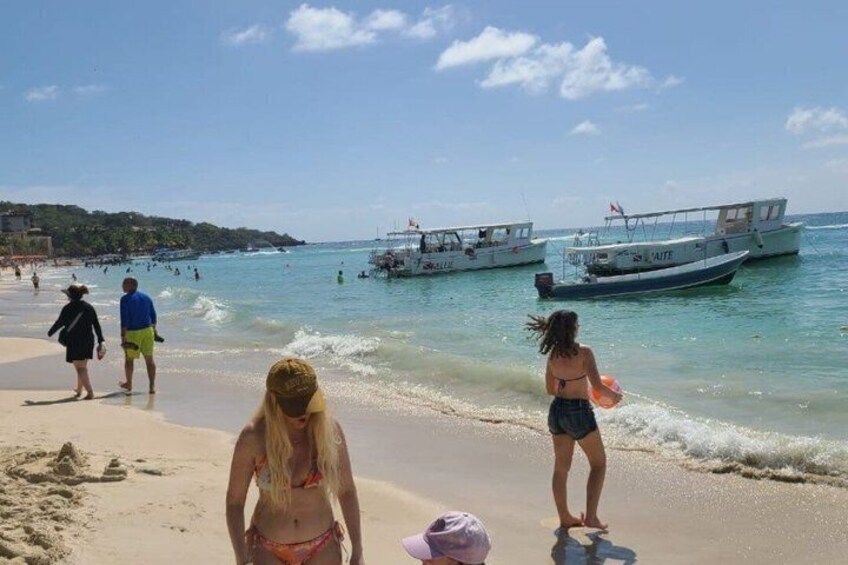 A beach with people, boats, and clear water. 5