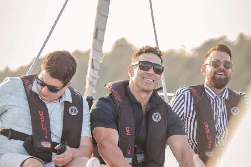 Three people on a sailboat wearing life jackets and sailing. 2