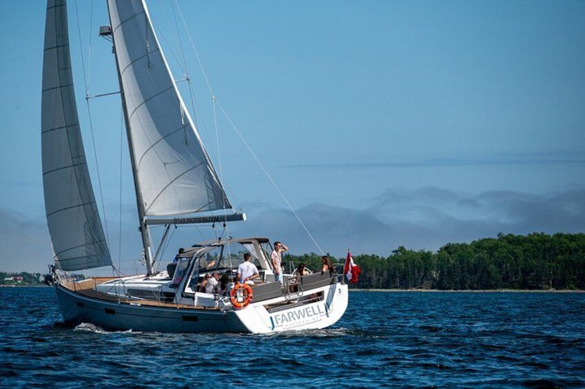 A sailboat named 'FARWELL' on the water with a forested coastline in the background. 5