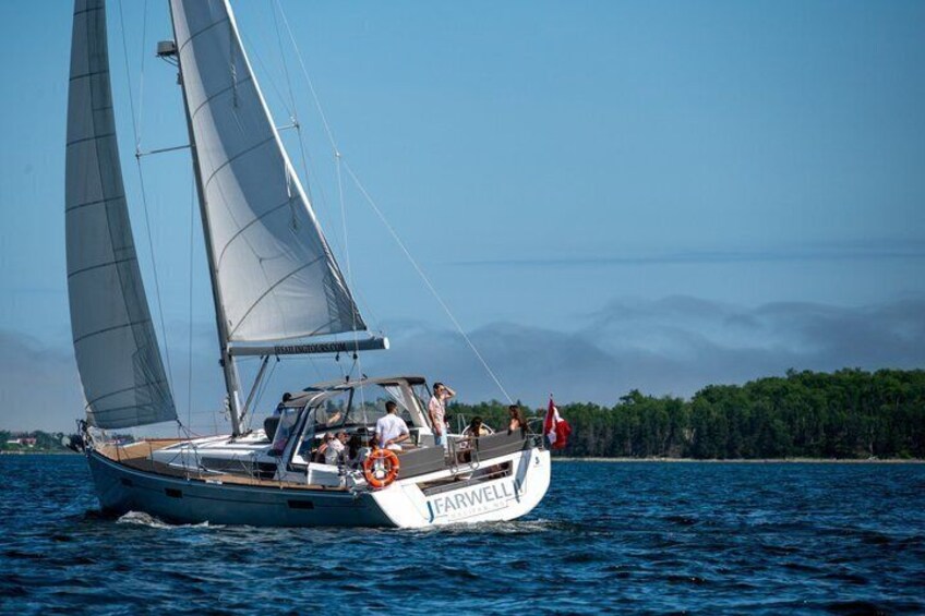 A sailboat named 'FARWELL' on the water with a forested coastline in the background. 5