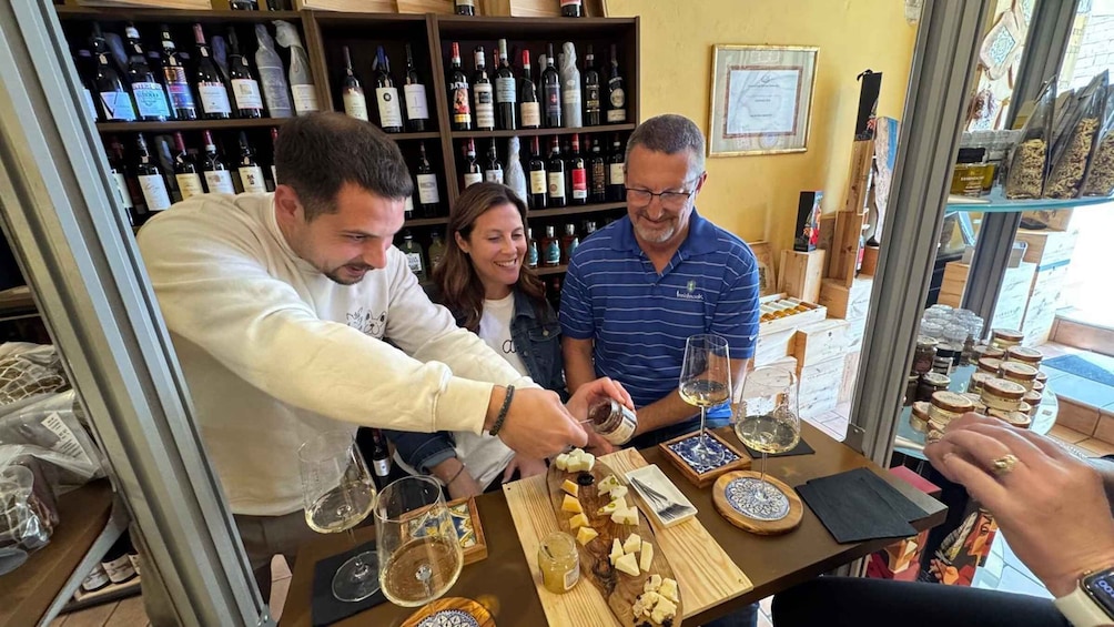A group of people at a wine tasting event with various bottles and cheeses on display. 1