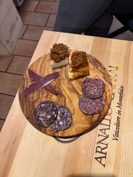 A wooden board with sliced salami, a piece of bread with meat topping, and a red meat slice. 5
