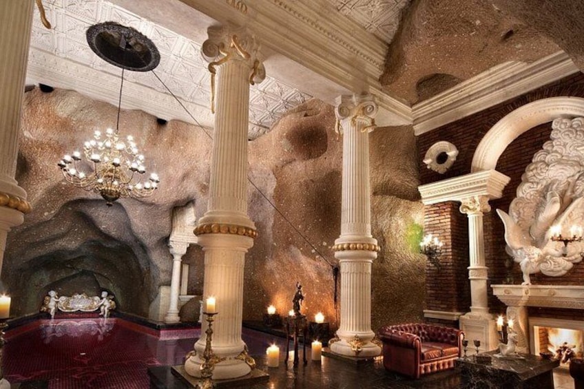 A grand interior with ornate columns, a chandelier, and a fireplace. 2