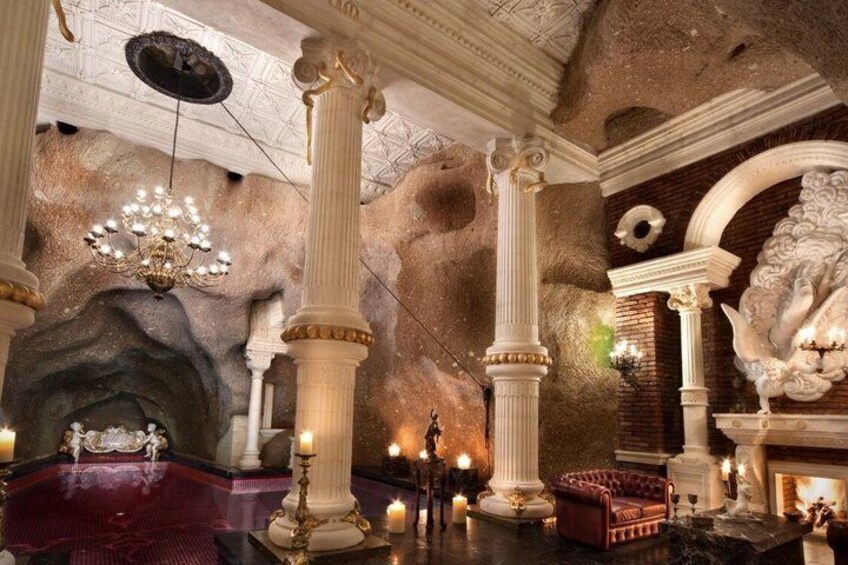 A grand interior with ornate columns, a chandelier, and a fireplace. 2