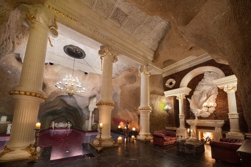 An ornate interior with columns, a chandelier, and a fireplace. 4