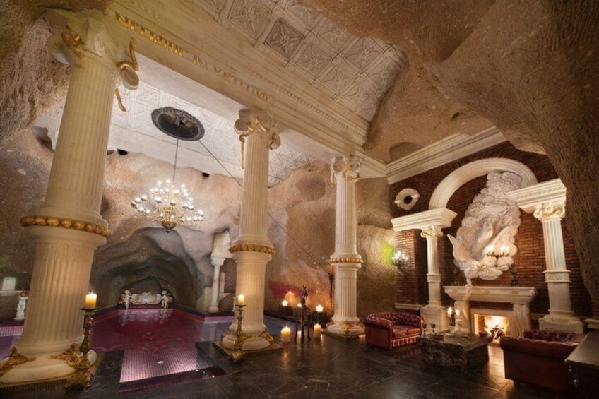 A grand hall with large columns, a chandelier, and a fireplace. 4