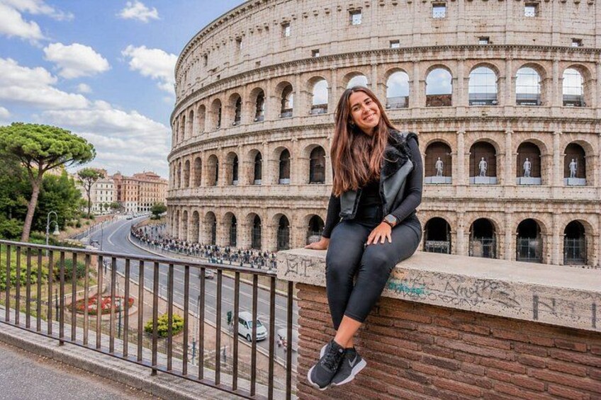 A person sitting on a wall in front of the Colosseum. 4