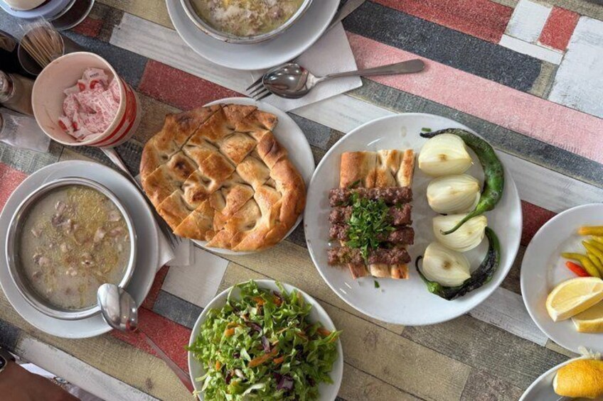 A table with various dishes including soup, a pie, meat with onions, and a salad. 1