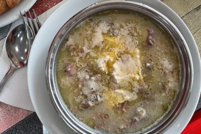 A bowl of soup with visible chunks of meat and a dollop of cream on top. 5
