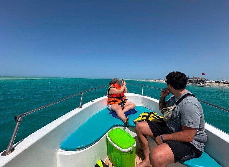 Two people on a boat with turquoise water and a clear sky. 4