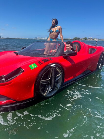 A red sports car on water with two people in swimwear. 3