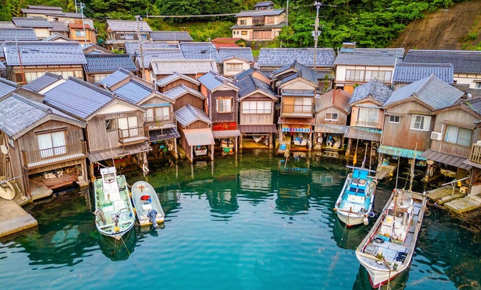 A traditional Japanese village with wooden houses and boats docked in a waterway. 2