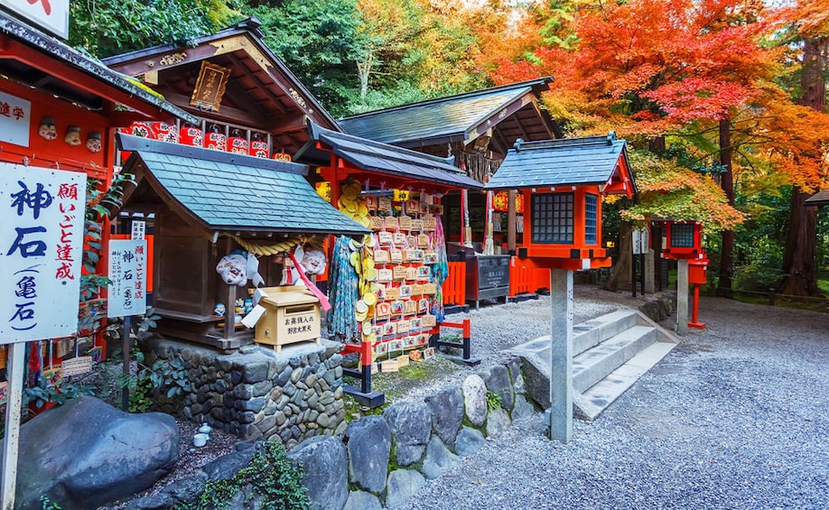 A traditional Japanese shrine with red and white structures, surrounded by autumn foliage. 3