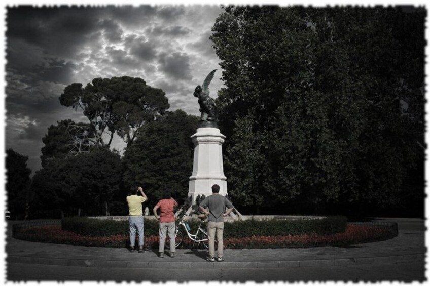 A statue in a park with people standing around it. 2