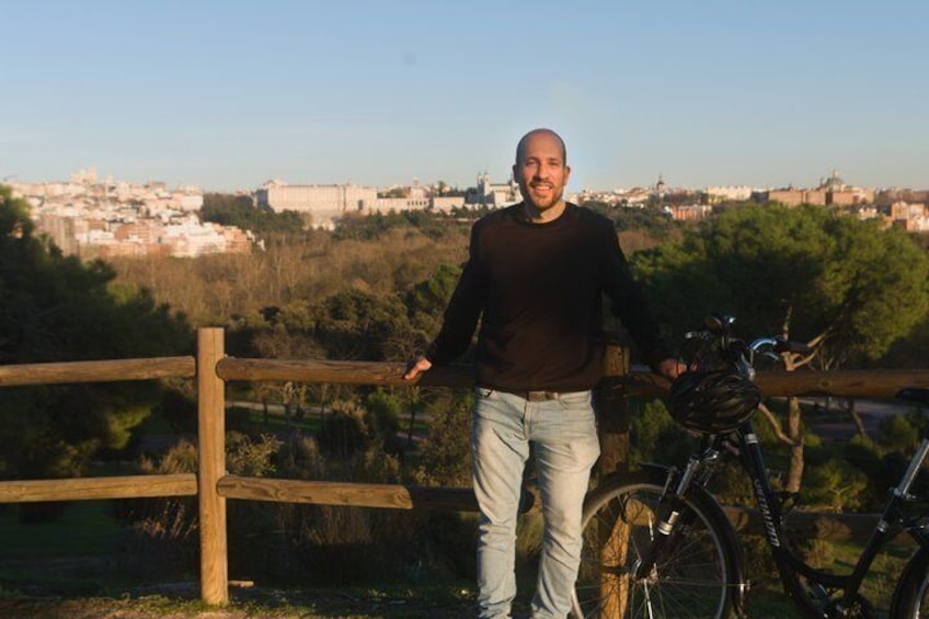 A man standing next to a bicycle with a cityscape in the background. 5