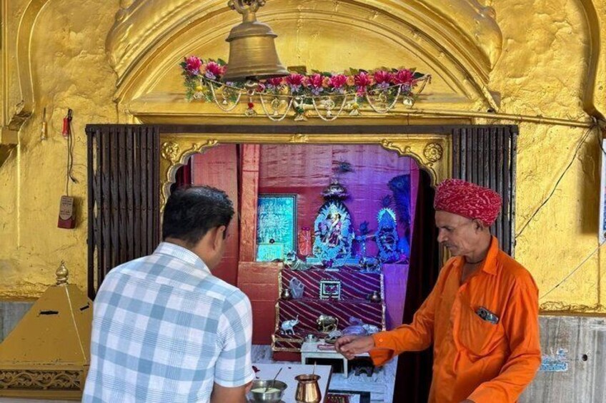 A religious ceremony with a golden shrine, a bell, and a person in orange attire. 2