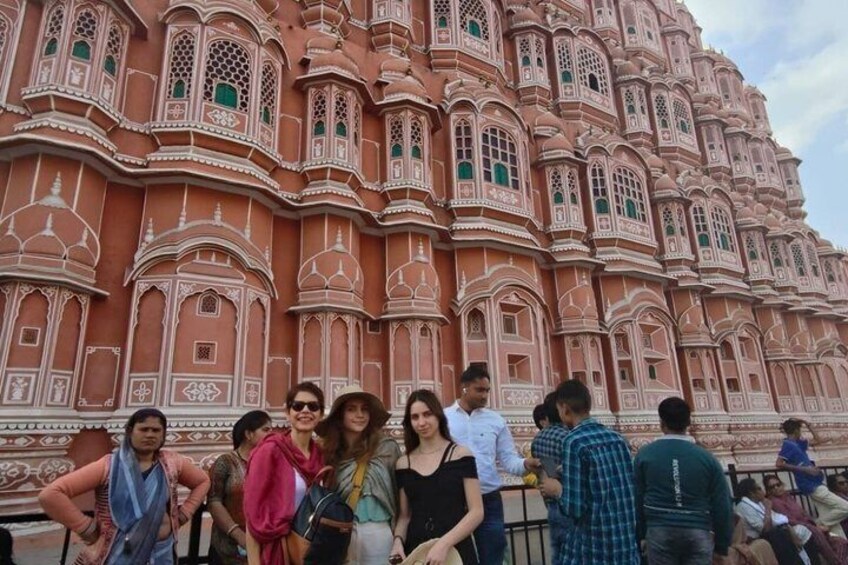 A group of people standing in front of a large, ornate building with intricate architectural details. 4