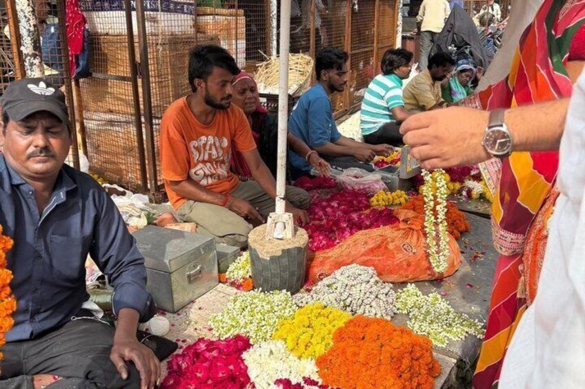 A market scene with people sitting and standing around tables filled with colorful flowers. 5