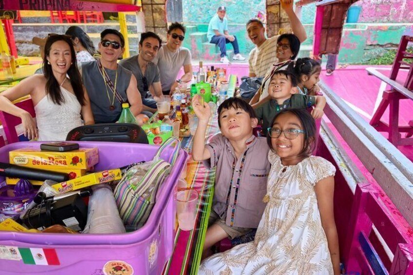 A group of people on a colorful ride with a purple cart, surrounded by vibrant decorations and a pink structure. 3