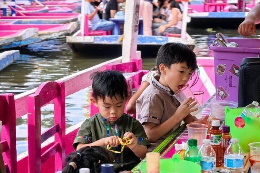 Two children on a boat with a table of drinks and snacks. 5