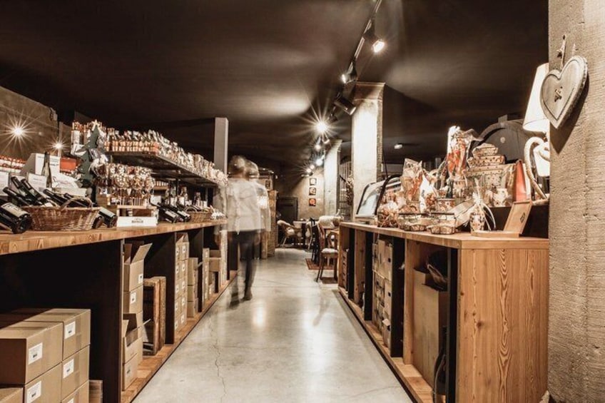 A narrow aisle with wooden shelves on either side, filled with various items and boxes. 4
