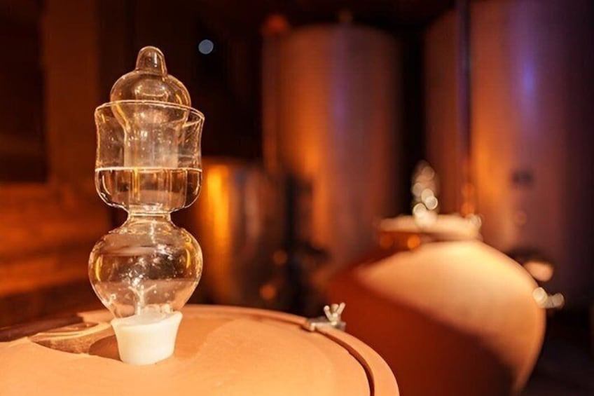 A clear glass object with a white substance, possibly a drink, on a surface with a blurred background of metallic structures. 3