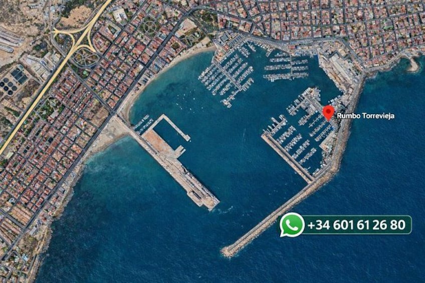 An aerial view of a coastal city with a prominent port, a large body of water, and a marked location named Rumbo Torrevieja. 2