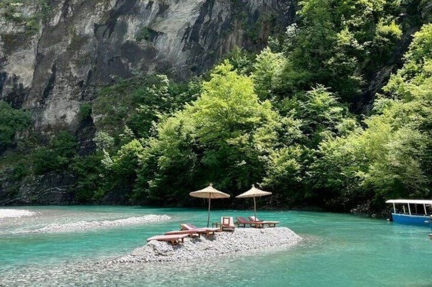 A secluded beach with clear turquoise water, surrounded by lush greenery and rocky cliffs. 2