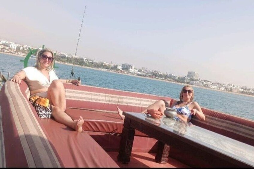 Two people relaxing on a boat with a cityscape in the background. 2