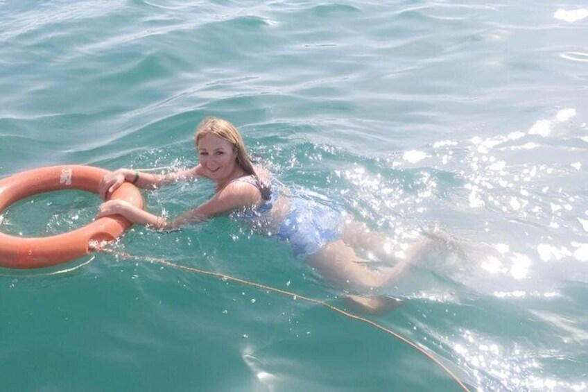 A person swimming in clear blue water with a floating ring. 3