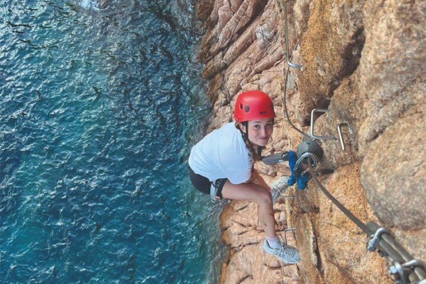 A person rock climbing on a cliff with a helmet and harness. 5