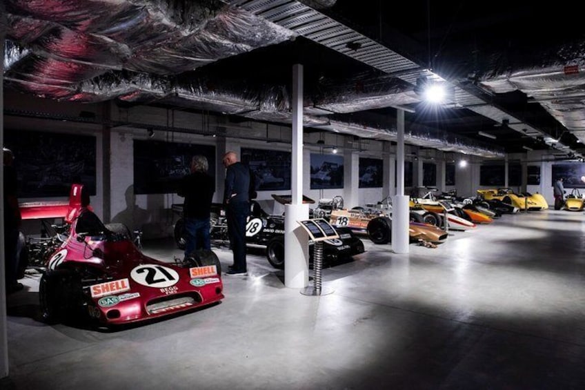 A garage with racing cars, including a red car with the number 21, and a yellow car with the number 18. 4