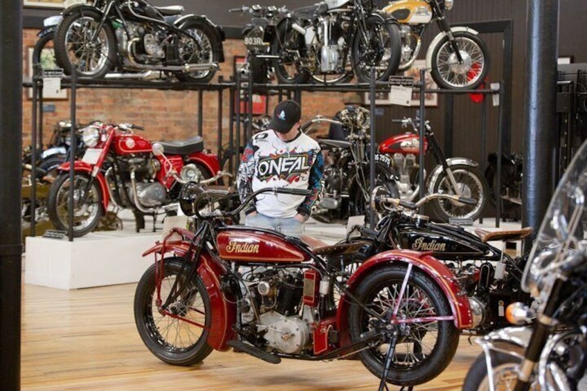 A motorcycle showroom with various models on display, including a red Indian motorcycle in the foreground. 5