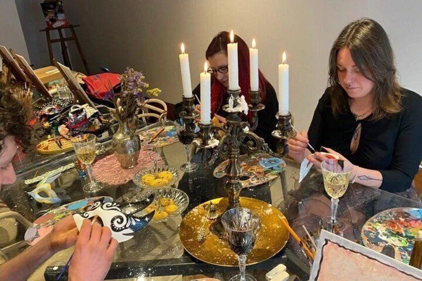 A group of people around a table with candles, plates of food, and drinks. 1