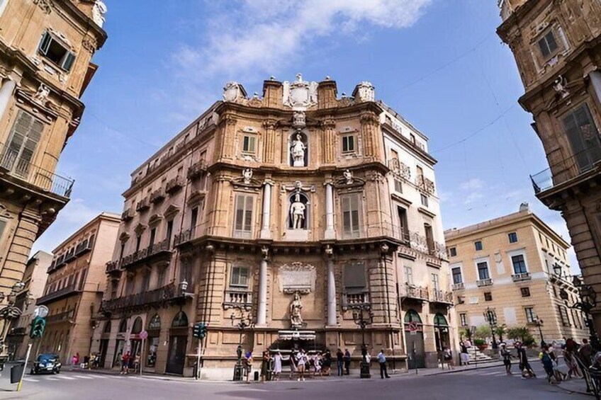 A historic building with ornate architecture, a street in front, and pedestrians. 1