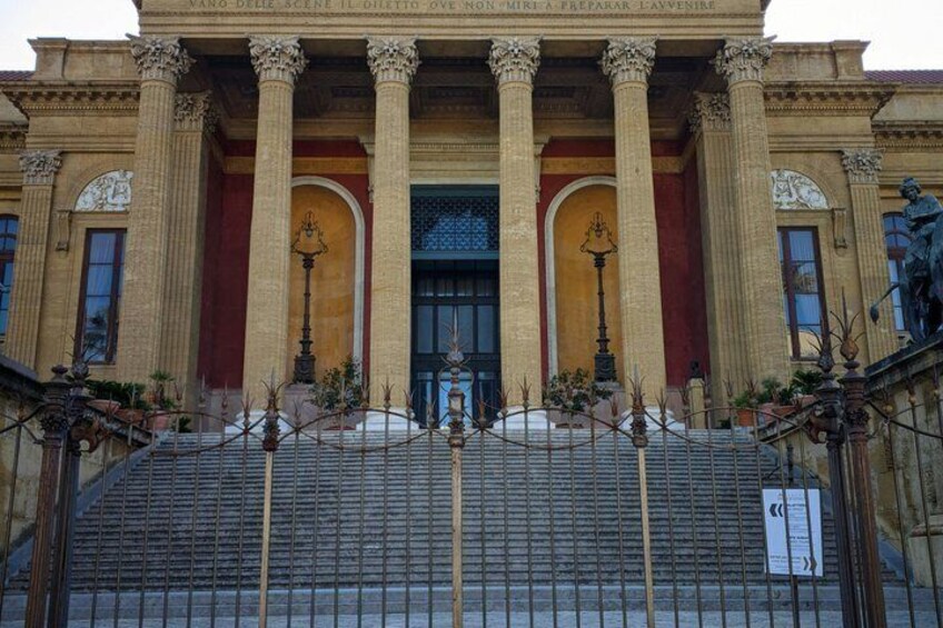 A classical building with columns, a central entrance, and a staircase leading up to the entrance. 3