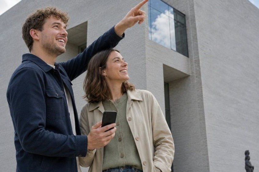 Two people standing in front of a modern building with a large window. 2