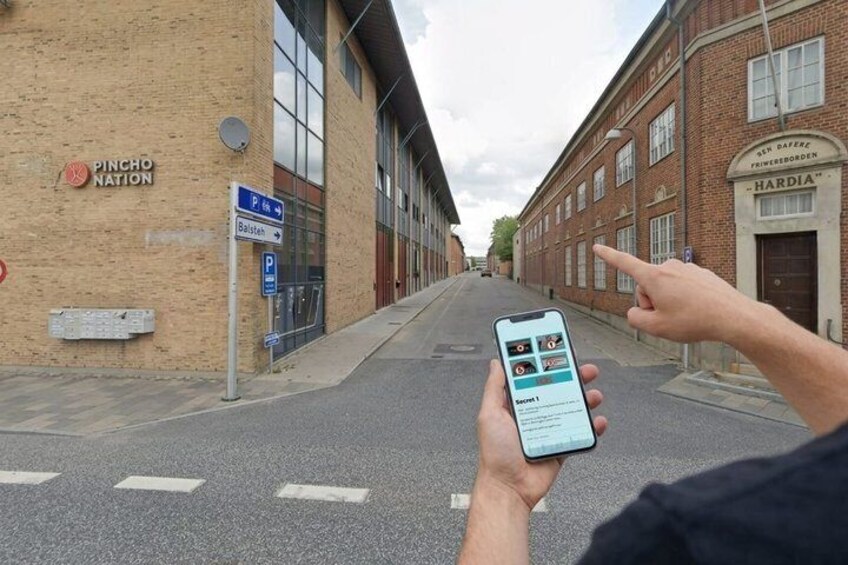 A person holding a smartphone with a parking app, a brick building labeled 'PINCHO NATION,' and a street with a blue parking sign. 3