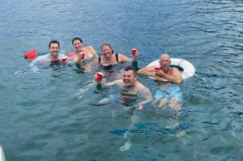 A group of people floating in a body of water, some holding red cups. 2