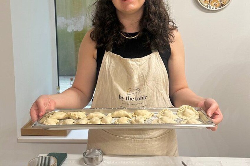 A person holding a tray of uncooked dumplings. 4