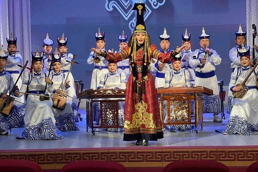 A traditional performance with a central figure in elaborate costume, flanked by musicians in white and blue attire. 2