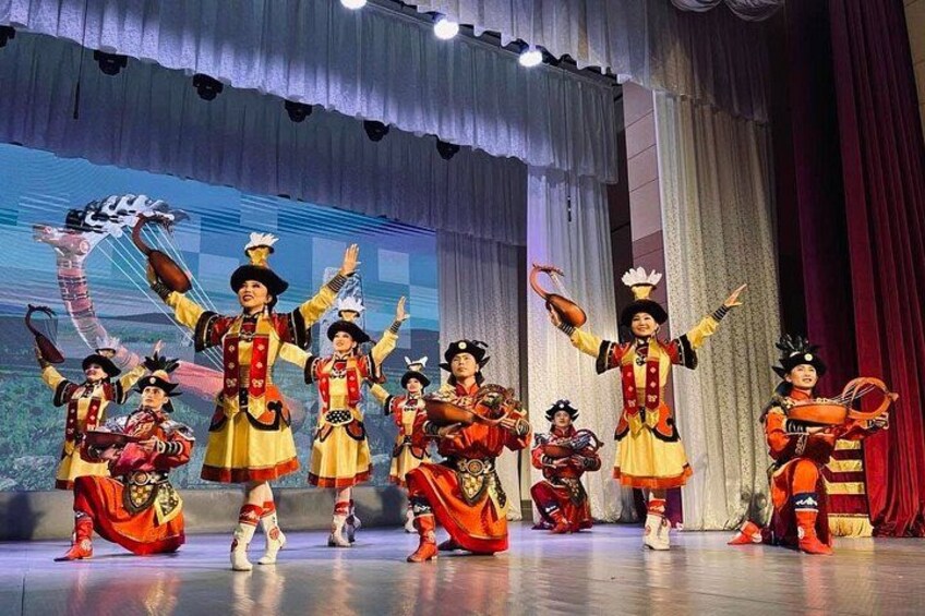 A stage with performers in traditional costumes, a backdrop with a landscape, and a curtain. 3