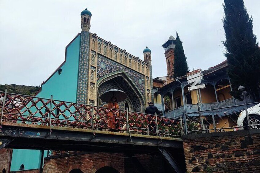 A bridge with a turquoise building and a mosque with a dome. 2