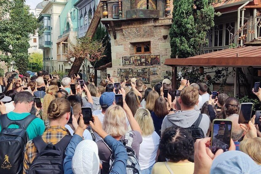 A crowd of people gathered around a building with a unique architectural style, possibly a historical or themed attraction. 3