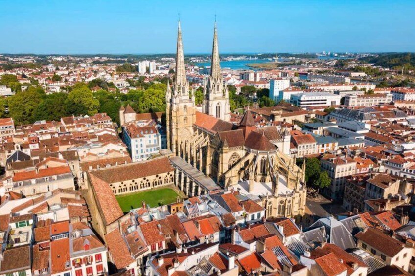 A cathedral with two spires, surrounded by a dense urban area with red-roofed buildings. 1