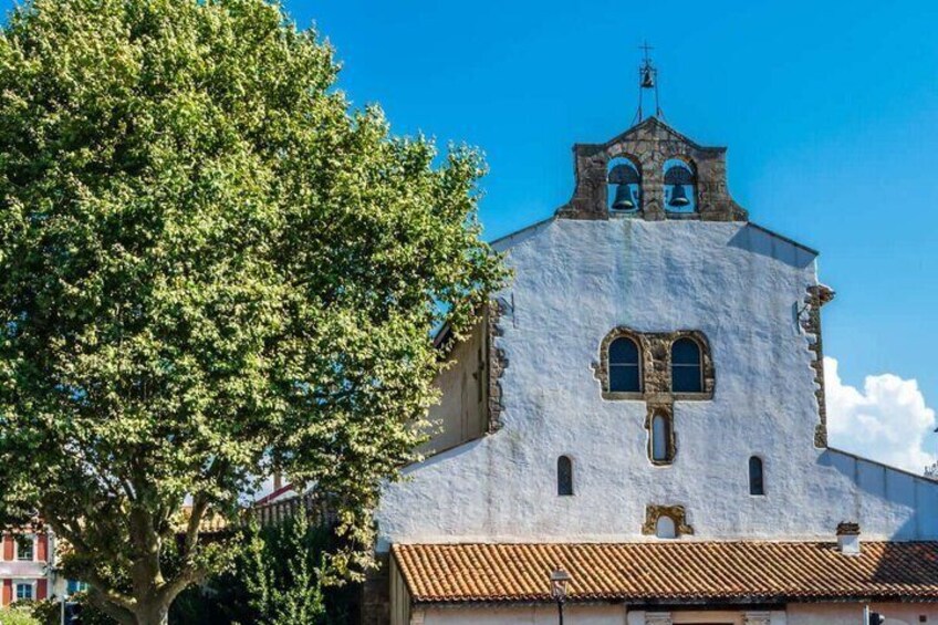 A church with a bell tower and a large tree in the foreground. 4