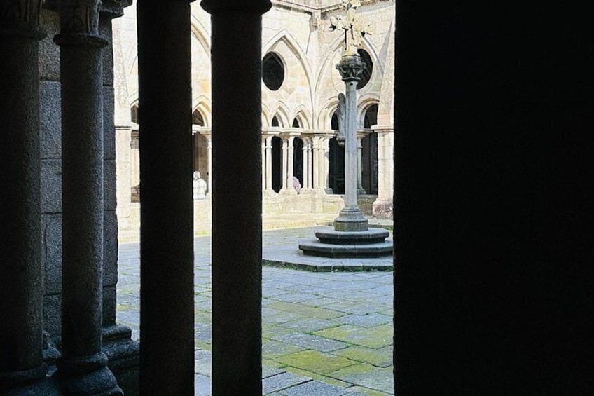 A courtyard with stone columns, a fountain, and gothic architecture. 5